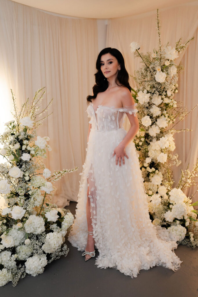 Model wearing wedding gown standing in front of deconstructed flower arches