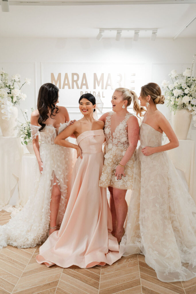 Bridal wear designer posing with models wearing her creations