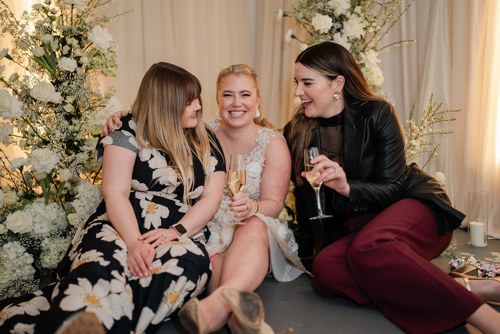 A photographer, bridal wear designer and florist sitting on the floor